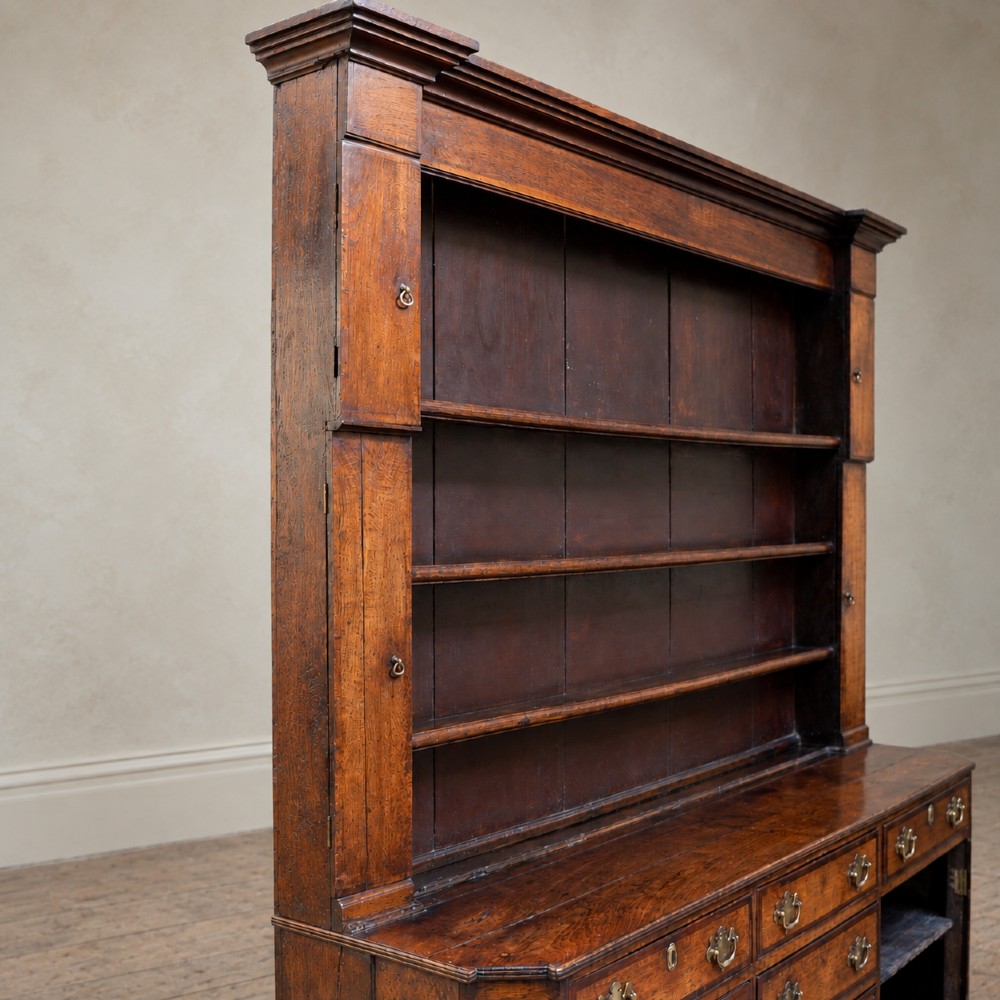 A George II dark oak dresser with a tall open plate rack above a sideboard featuring multiple drawers and twin cupboard doors. View VII