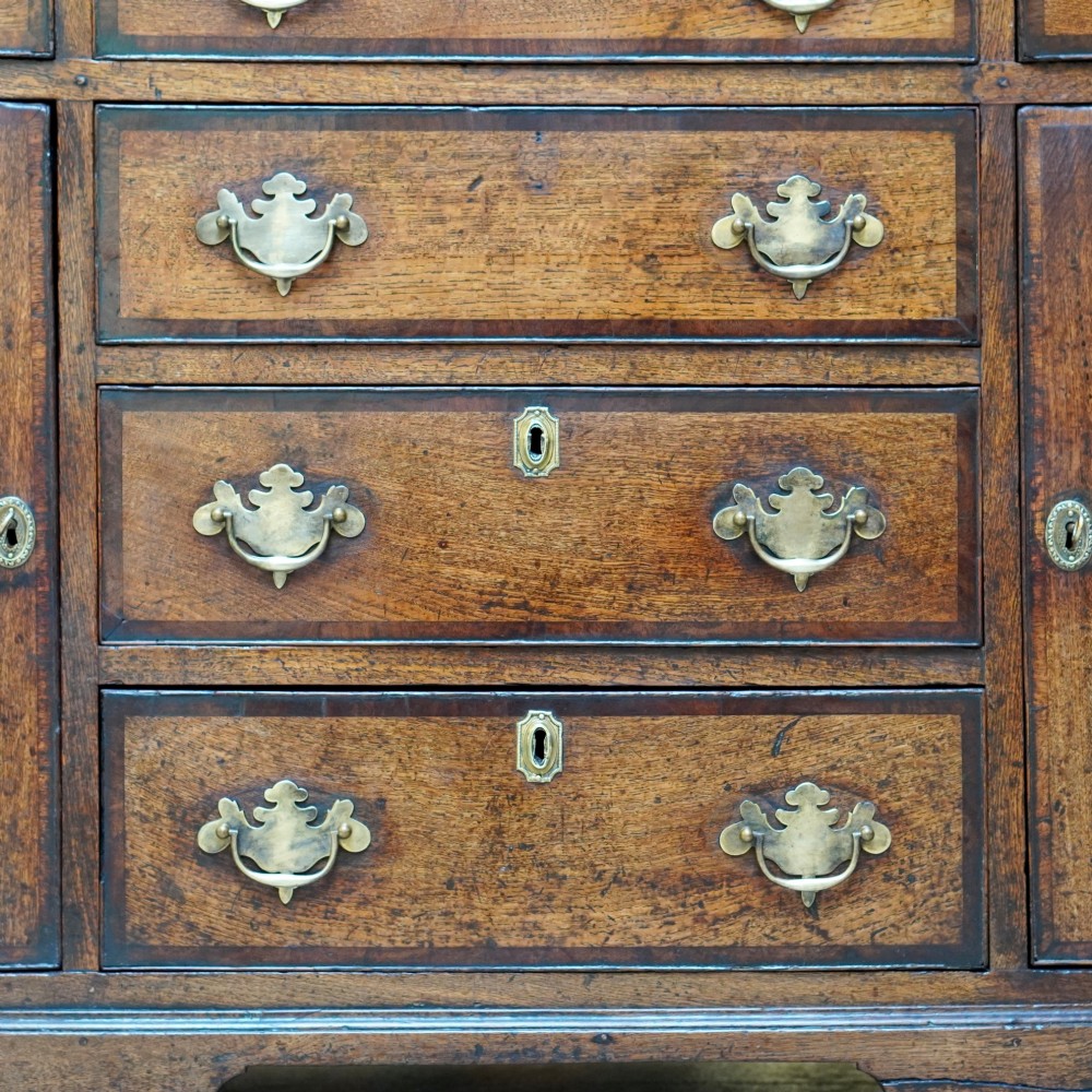 A George II dark oak dresser with a tall open plate rack above a sideboard featuring multiple drawers and twin cupboard doors. View X