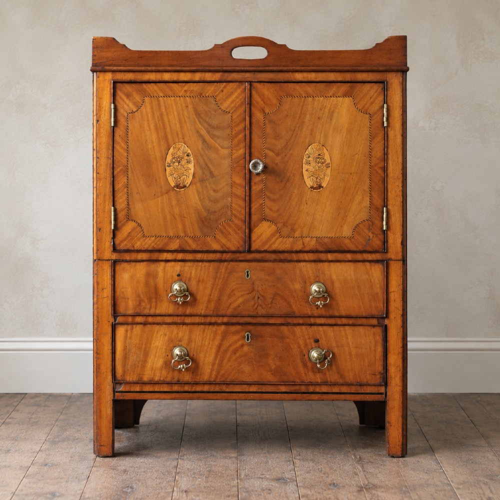 A 19th-century mahogany tray top night commode featuring two cabinet doors with oval marquetry inlays above two drawers with brass handles.