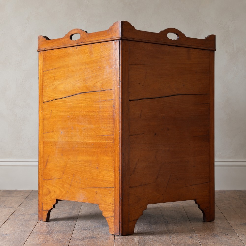 A 19th-century mahogany tray top night commode featuring two cabinet doors with oval marquetry inlays above two drawers with brass handles. View V