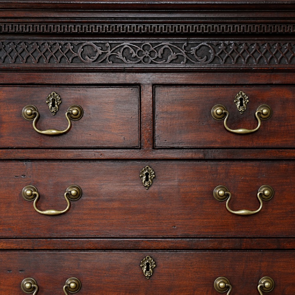 A George III mahogany chest on chest featuring two short over six long graduated drawers, a brushing slide, blind fretwork frieze, brass swan-neck handles, and bracket feet. View II