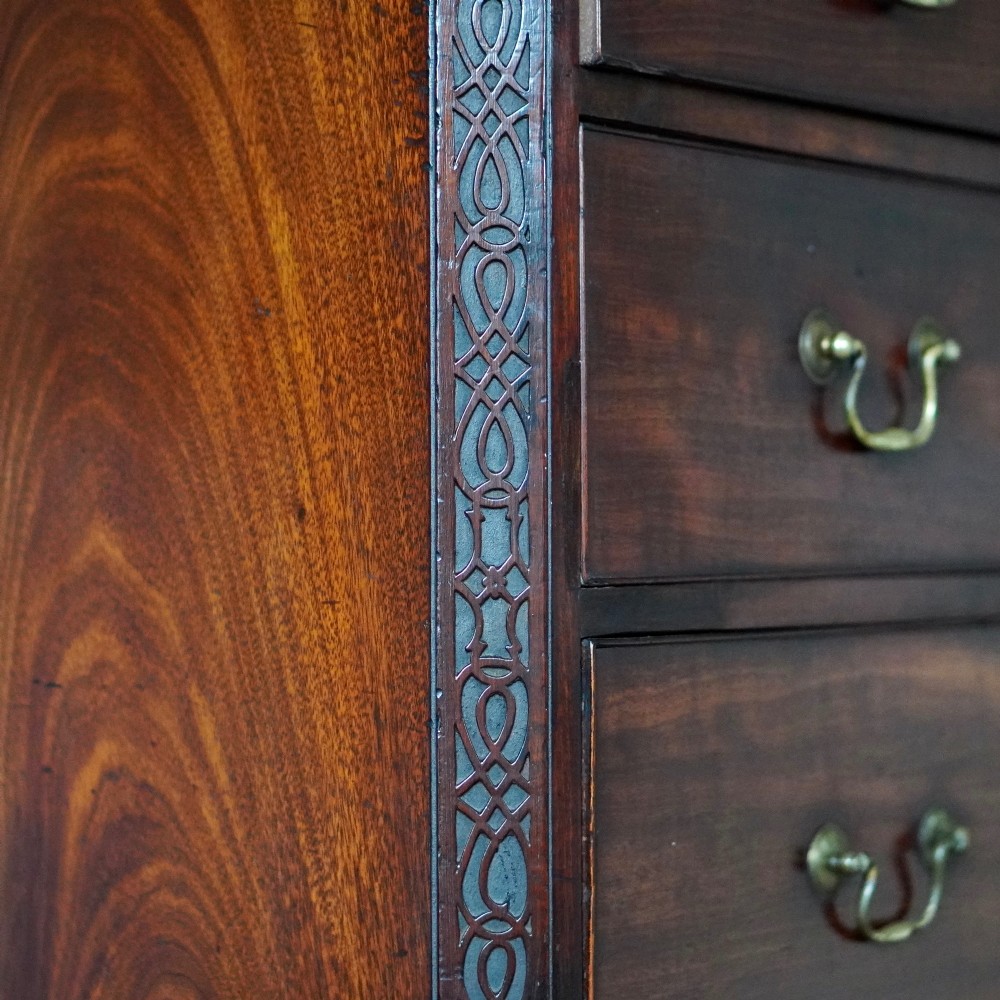 A George III mahogany chest on chest featuring two short over six long graduated drawers, a brushing slide, blind fretwork frieze, brass swan-neck handles, and bracket feet. View IX
