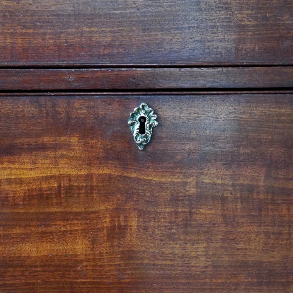 A George III mahogany chest on chest featuring two short over six long graduated drawers, a brushing slide, blind fretwork frieze, brass swan-neck handles, and bracket feet. View XII