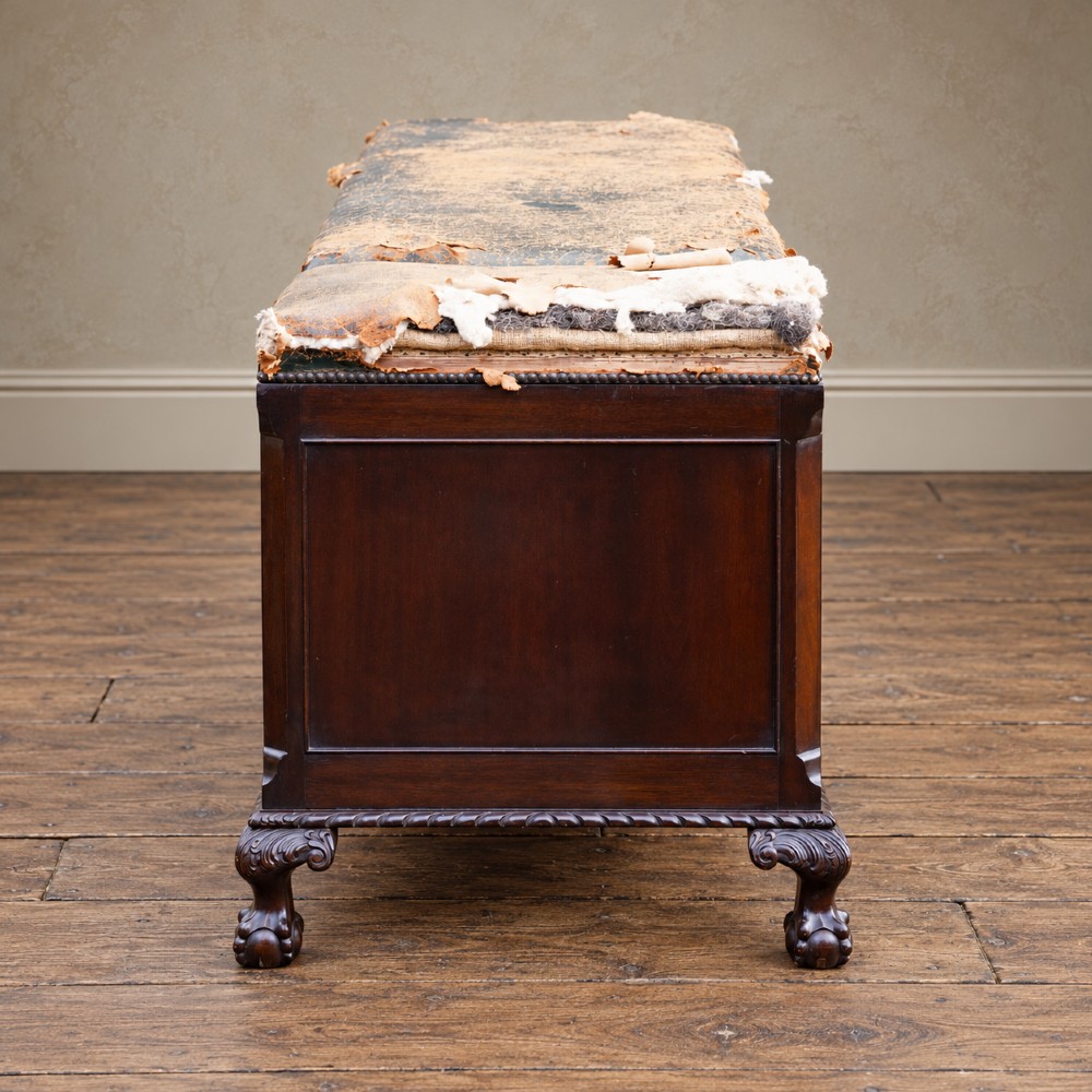 A long antique dark mahogany bench with four panelled cupboard doors, carved ball and claw feet, and a worn leather cushion top with a raised headrest. View XIII
