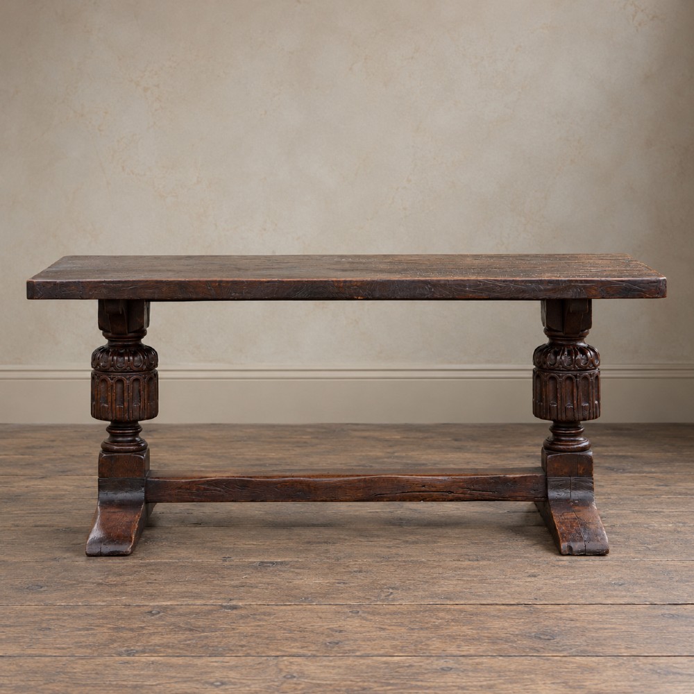 A 17th-century oak and elm refectory dining table featuring a solid single-plank top over thick carved bulbous pedestal supports and a low central stretcher rail.