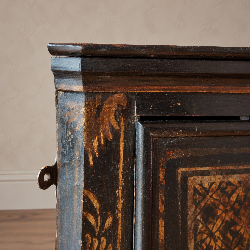 An 18th-century black japanned single-door wall corner cupboard featuring hand-painted gold Chinoiserie figures, architectural motifs, and brass butterfly hinges. View VII