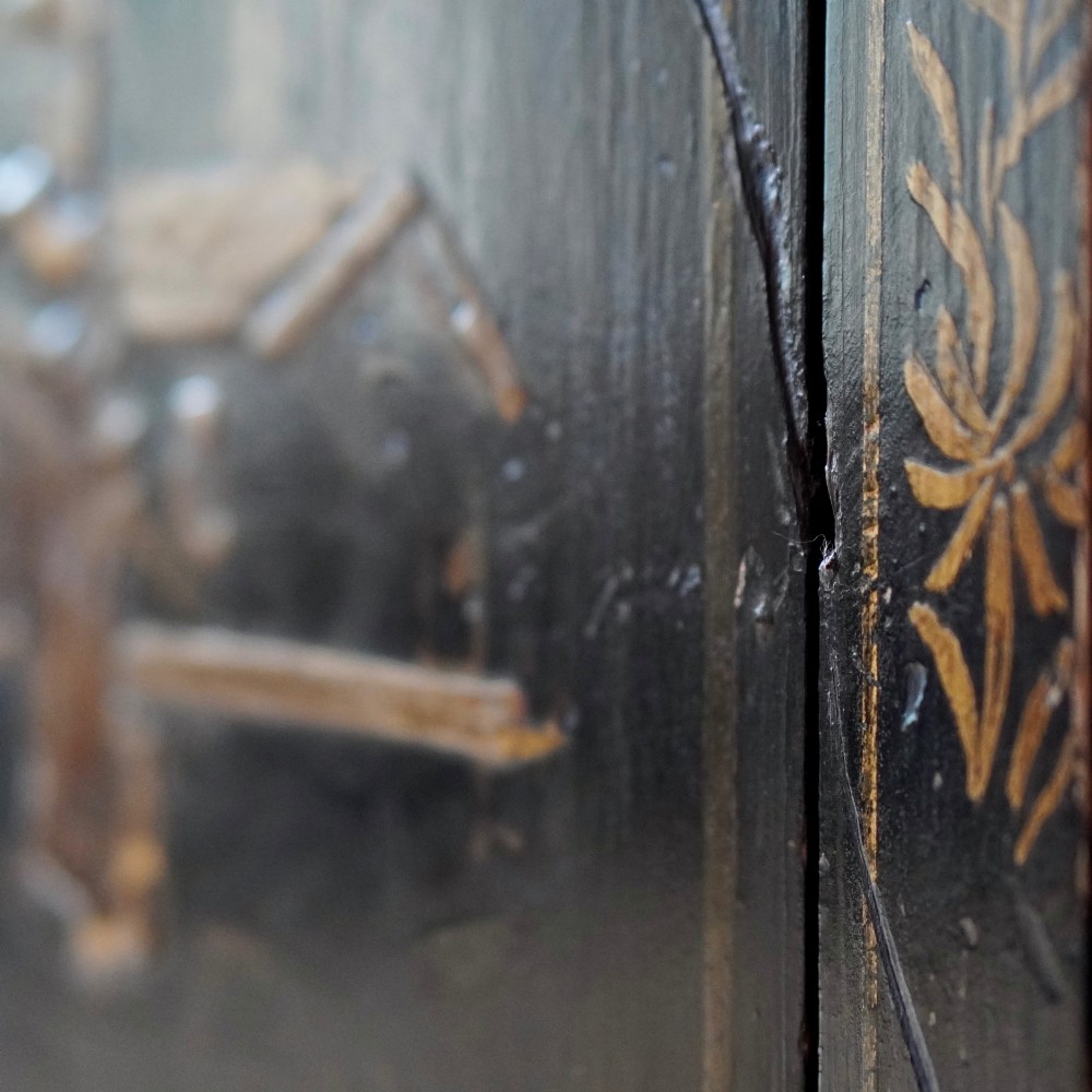 An 18th-century black japanned single-door wall corner cupboard featuring hand-painted gold Chinoiserie figures, architectural motifs, and brass butterfly hinges. View IX