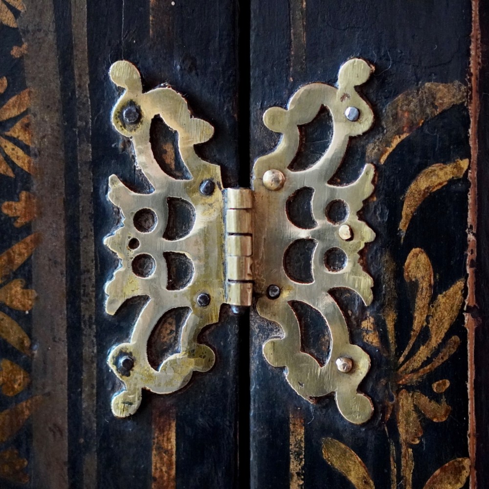 An 18th-century black japanned single-door wall corner cupboard featuring hand-painted gold Chinoiserie figures, architectural motifs, and brass butterfly hinges. View X