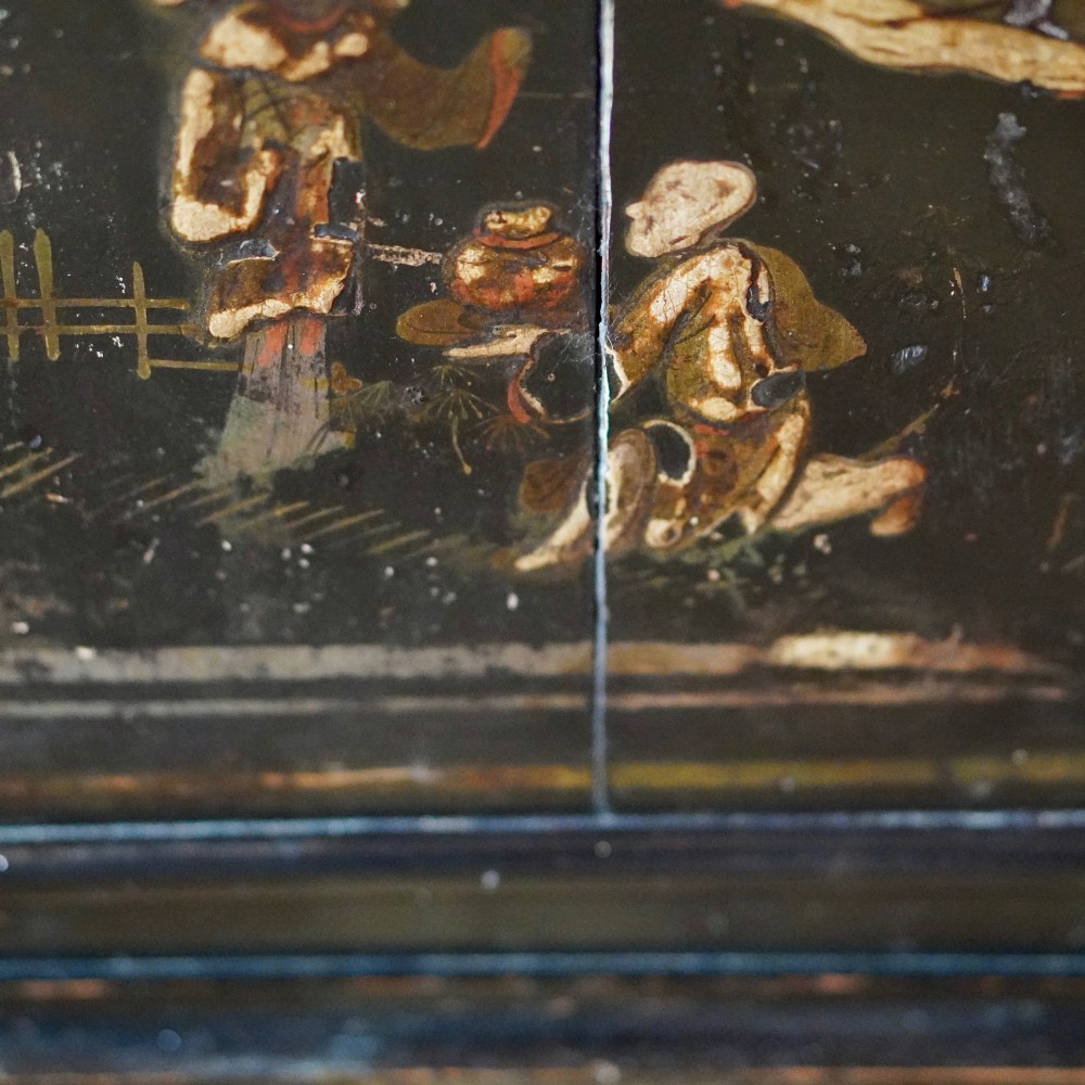 An 18th-century black japanned single-door wall corner cupboard featuring hand-painted gold Chinoiserie figures, architectural motifs, and brass butterfly hinges. View XIII