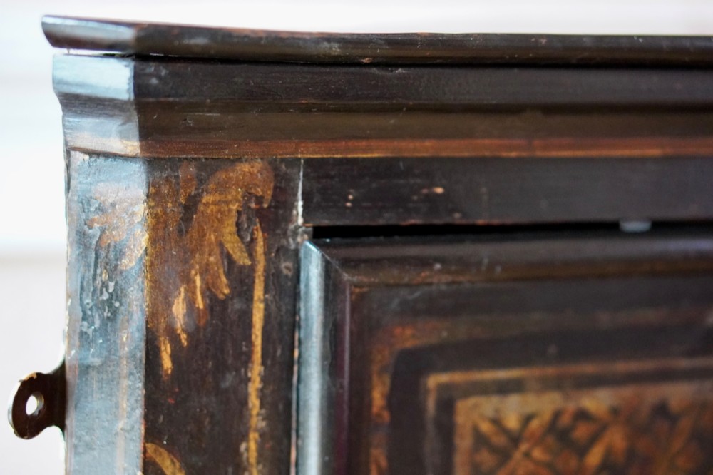 An 18th-century black japanned single-door wall corner cupboard featuring hand-painted gold Chinoiserie figures, architectural motifs, and brass butterfly hinges. View XIV