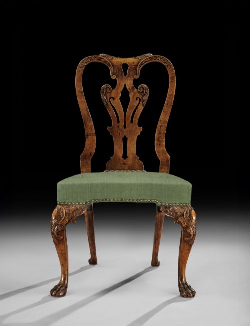 fig 1. A pair of George II carved walnut side chairs featuring pierced splat backs, green upholstered seats, and carved cabriole legs terminating in claw and ball feet.