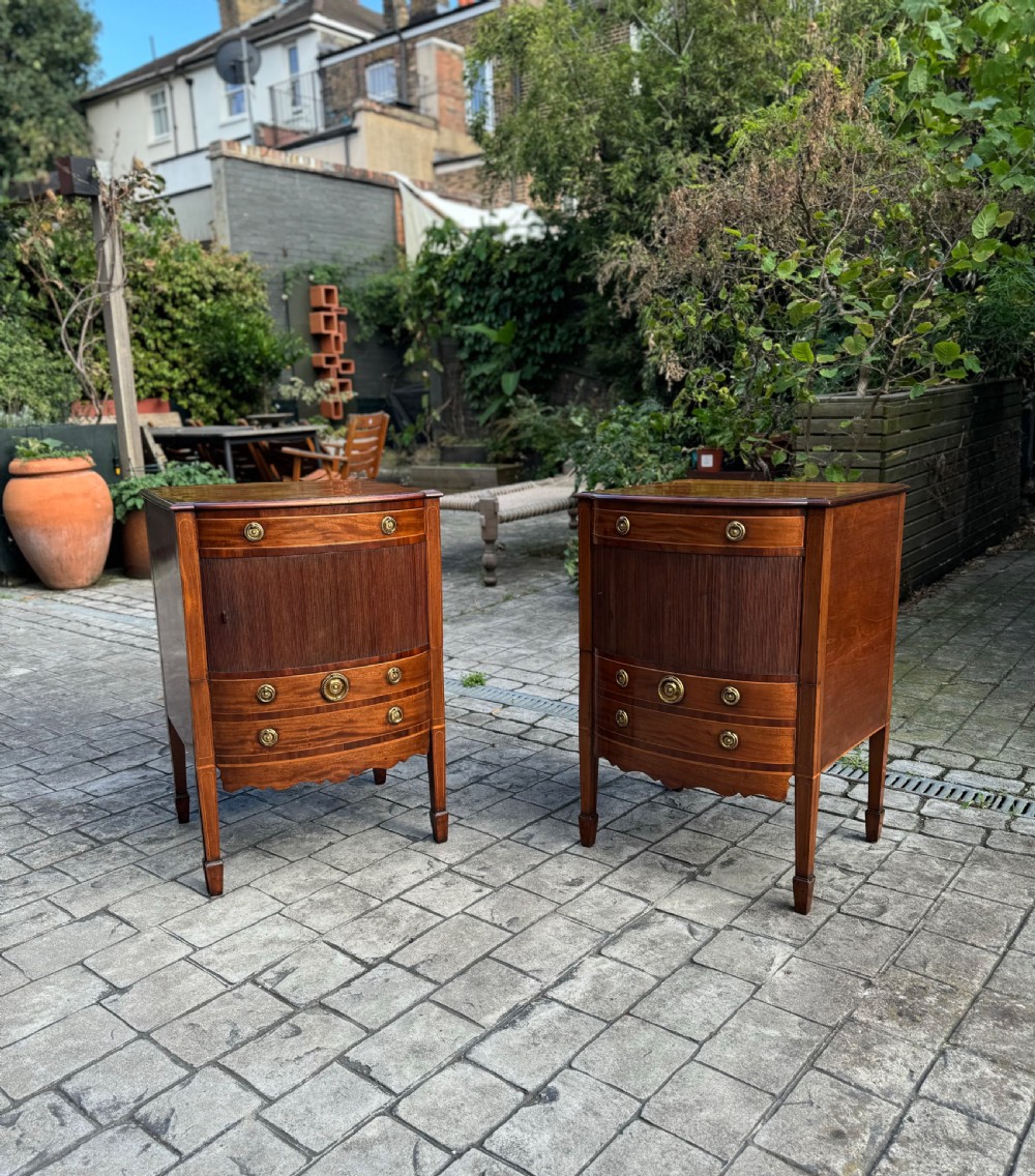 A pair of George III mahogany bedside cabinets featuring tambour slatted doors, brass ring handles, satinwood inlay, and tapered legs. View II