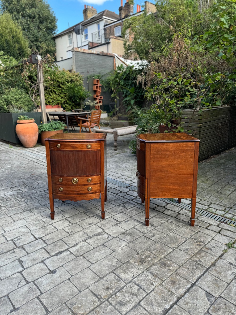 A pair of George III mahogany bedside cabinets featuring tambour slatted doors, brass ring handles, satinwood inlay, and tapered legs. View III