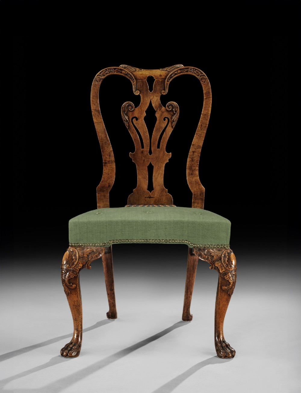 A pair of George II carved walnut side chairs featuring pierced splat backs, green upholstered seats, and carved cabriole legs terminating in claw and ball feet. View II