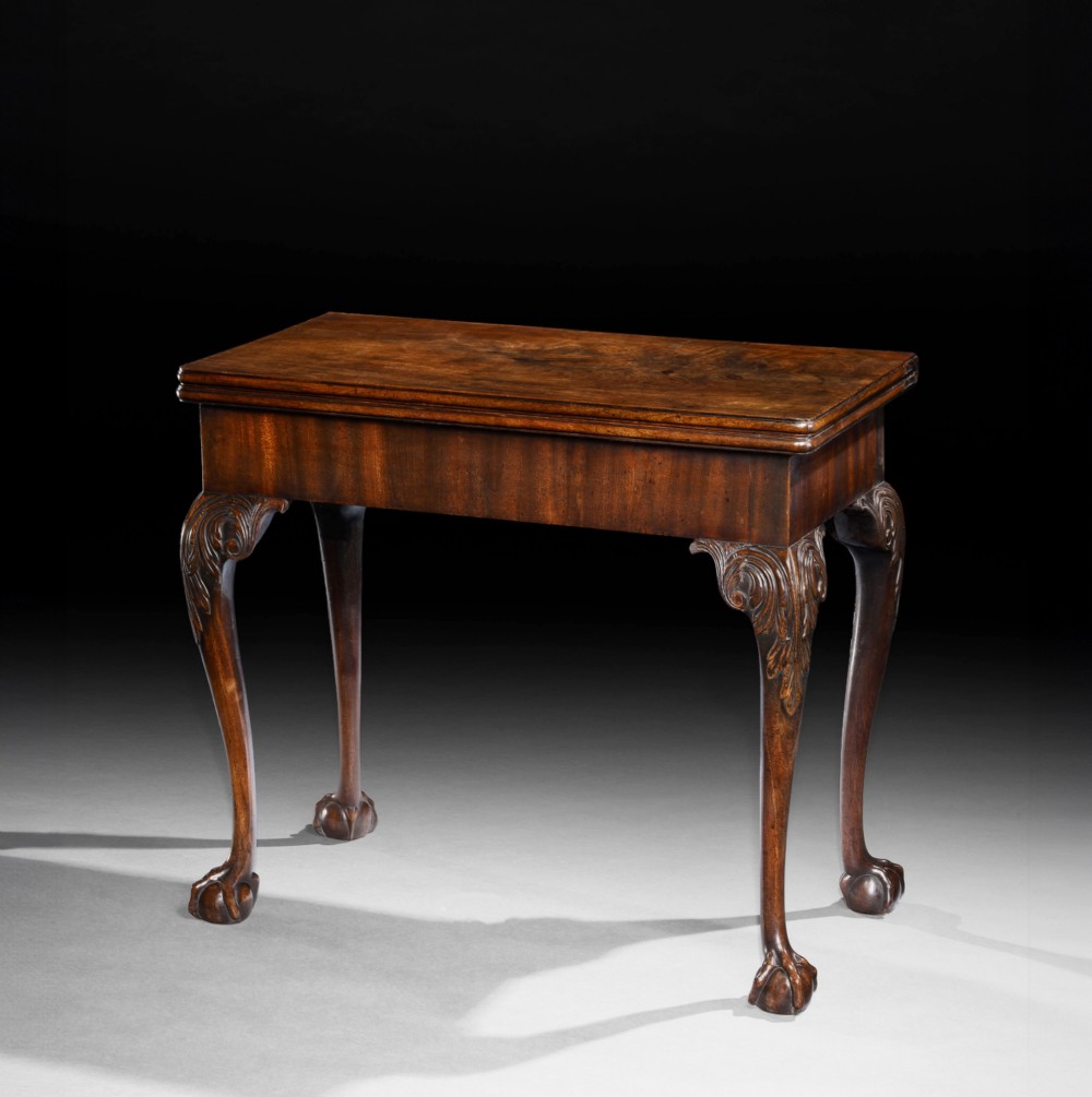 A George II mahogany fold-over card table featuring carved acanthus knees, cabriole legs, and claw and ball feet.