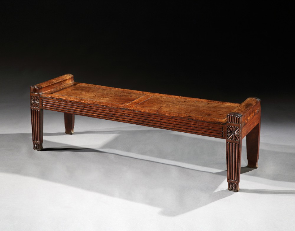 A long Regency mahogany window seat featuring reeded legs, carved star-motif corner blocks, and raised scrolled ends.