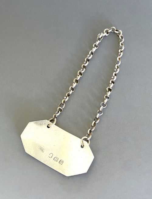 fig 1. A Georgian sterling silver octagonal decanter label engraved with the word RUM suspended on a fine silver chain.