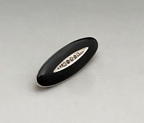 fig 1. An oval black enamel silver brooch featuring a central navette-shaped aperture inset with a line of small seed pearls.