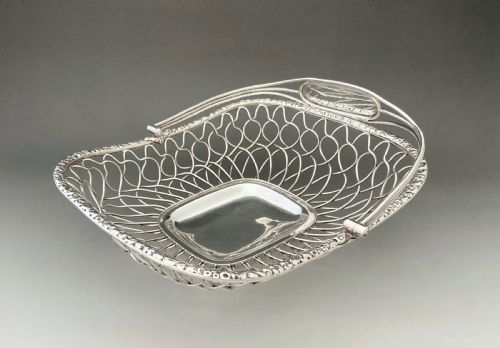 fig 1. A Georgian silver-plated wirework basket featuring an arched swing handle, open lattice sides, and a polished solid central base.