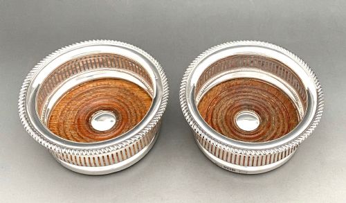 fig 1. A pair of circular sterling silver wine coasters with pierced side galleries, gadrooned rims, and turned wood bases with central silver buttons.
