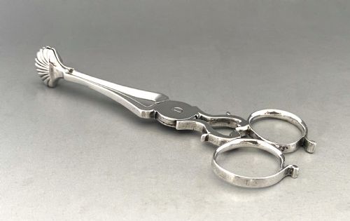 fig 1. A pair of 18th-century silver scissor-action sugar nips with shell-shaped grips and an engraved monogram on the central pivot.