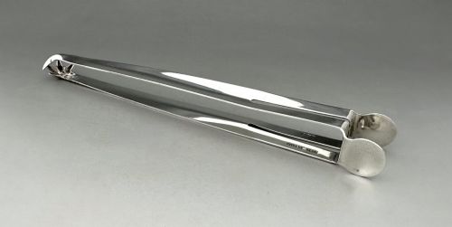 fig 1. A pair of polished silver Edwardian bar tongs featuring slender arms with mechanical claw gripping ends and flat finger pads.