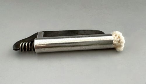 fig 1. An antique Victorian silver tinder tube with engraved maker details, a steel striker plate, and a protruding cotton wick.
