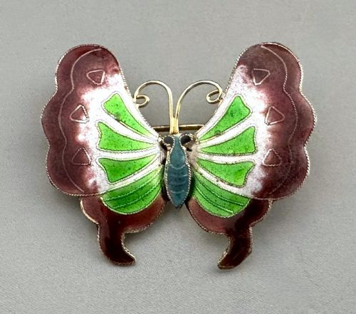 fig 1. An antique butterfly brooch constructed from silver gilt and detailed with green, white, and burgundy enamel on the wings.