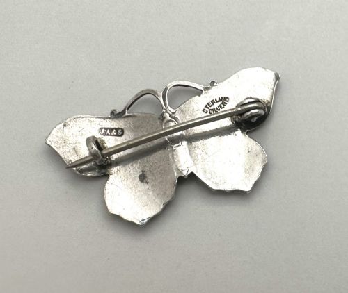 fig 2. An Edwardian silver butterfly brooch featuring purple textured guilloche enamel wings and a green enamelled body.