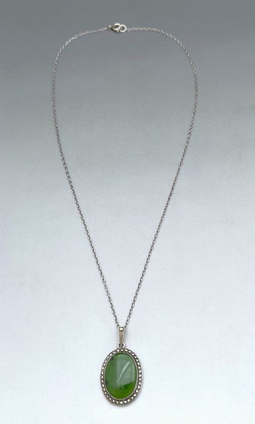 fig 1. An oval green jade cabochon pendant set in a decorative silver border on a fine silver link chain.