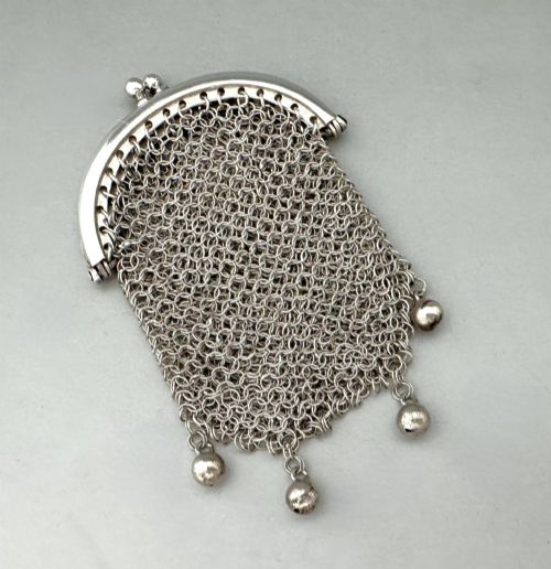 fig 1. A petite French silver chainmail purse featuring a curved kiss-clasp frame and small silver spherical drops attached along the bottom seam.