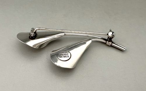 fig 1. A sterling silver brooch depicting two stylized calla lily flowers with white engine-turned guilloche enamel petals.