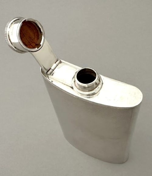 An Art Deco silver curved hip flask featuring fine engine-turned geometric detailing and a hinged cap. View VI
