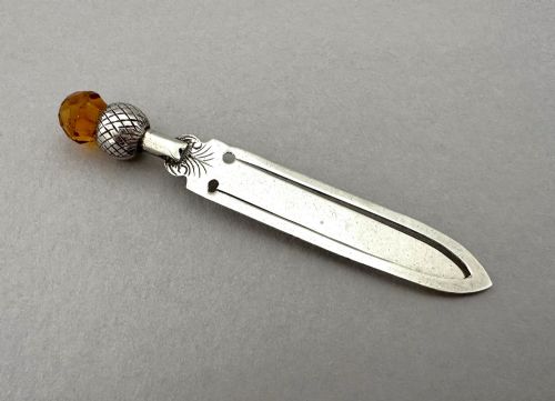fig 1. A silver bookmark clip with engraved leaf detailing, topped with an amber gemstone thistle terminal.