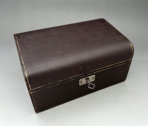 fig 1. A dark brown leather Victorian jewellery box with a domed lid, subtle gilt edge tooling, and a metal keyhole escutcheon.