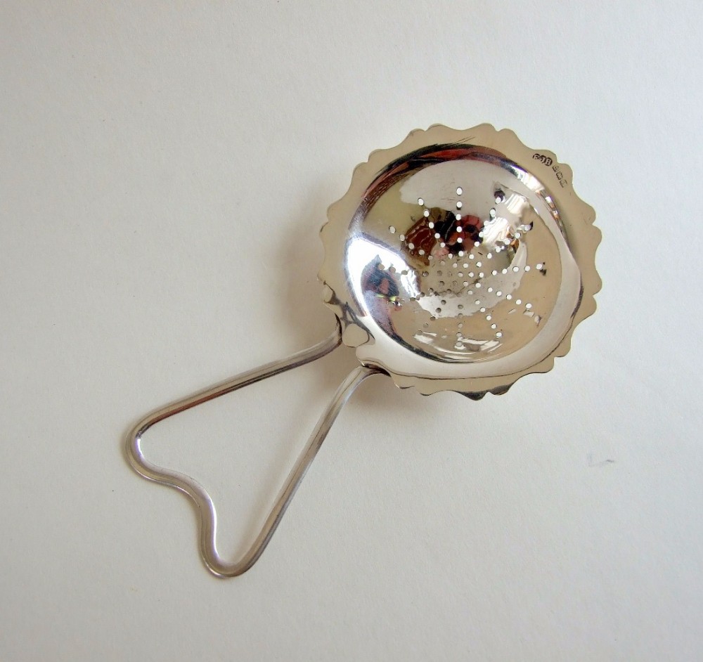 An unusual George V silver tea strainer.