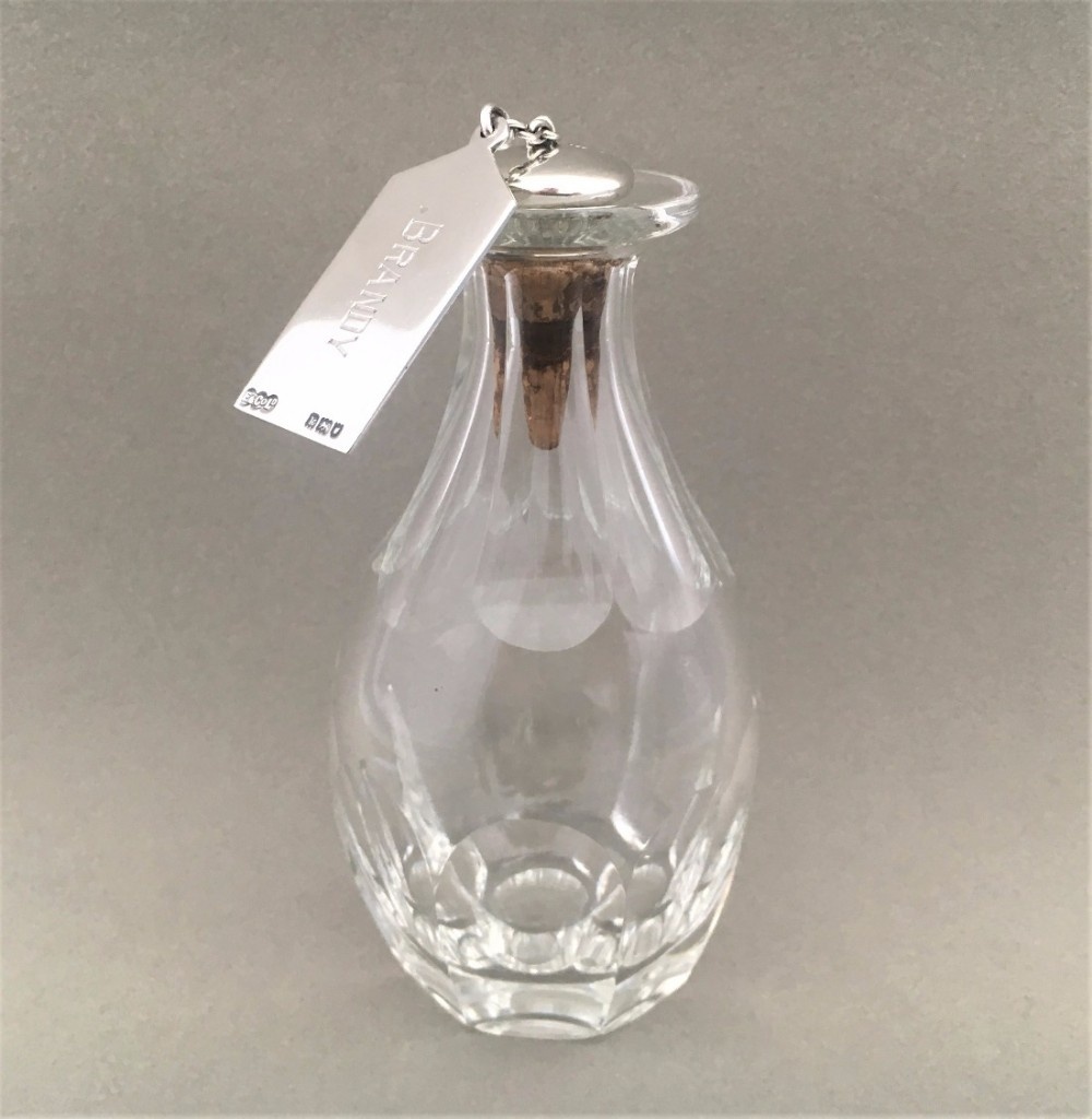 An unusual and rare Silver brandy label, stopper and solo glass decanter.