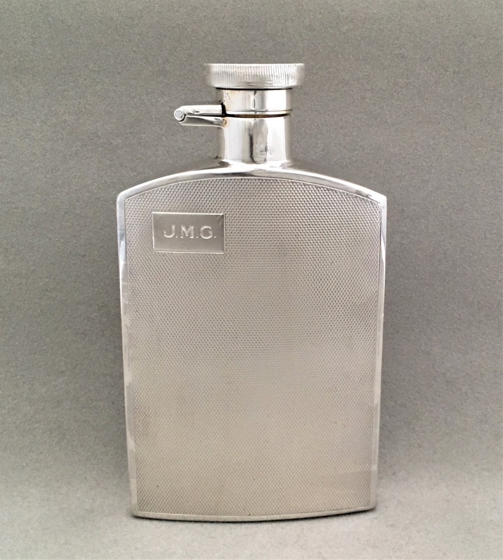 A silver hip flask with engine turned panels