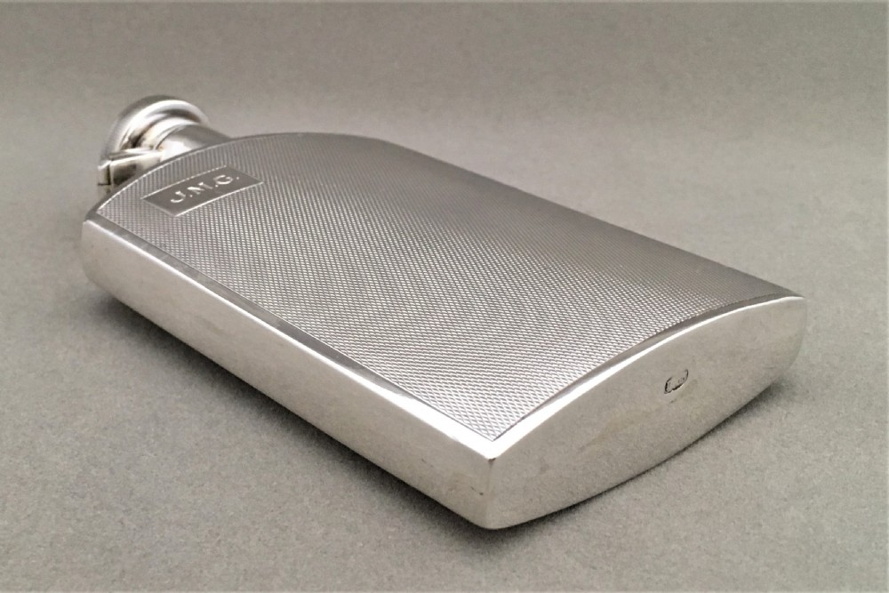 A silver hip flask with engine turned panels View VI