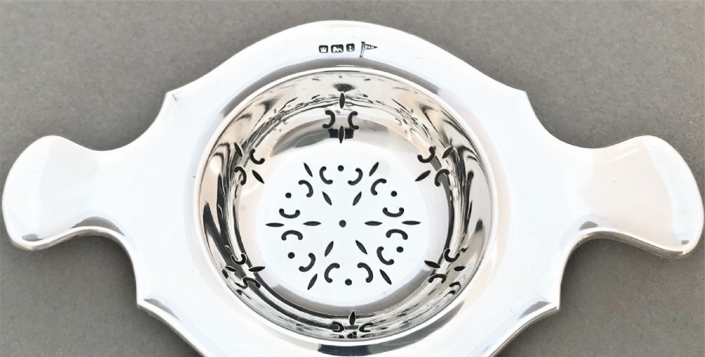 A gorgeous twin handled silver tea strainer View II