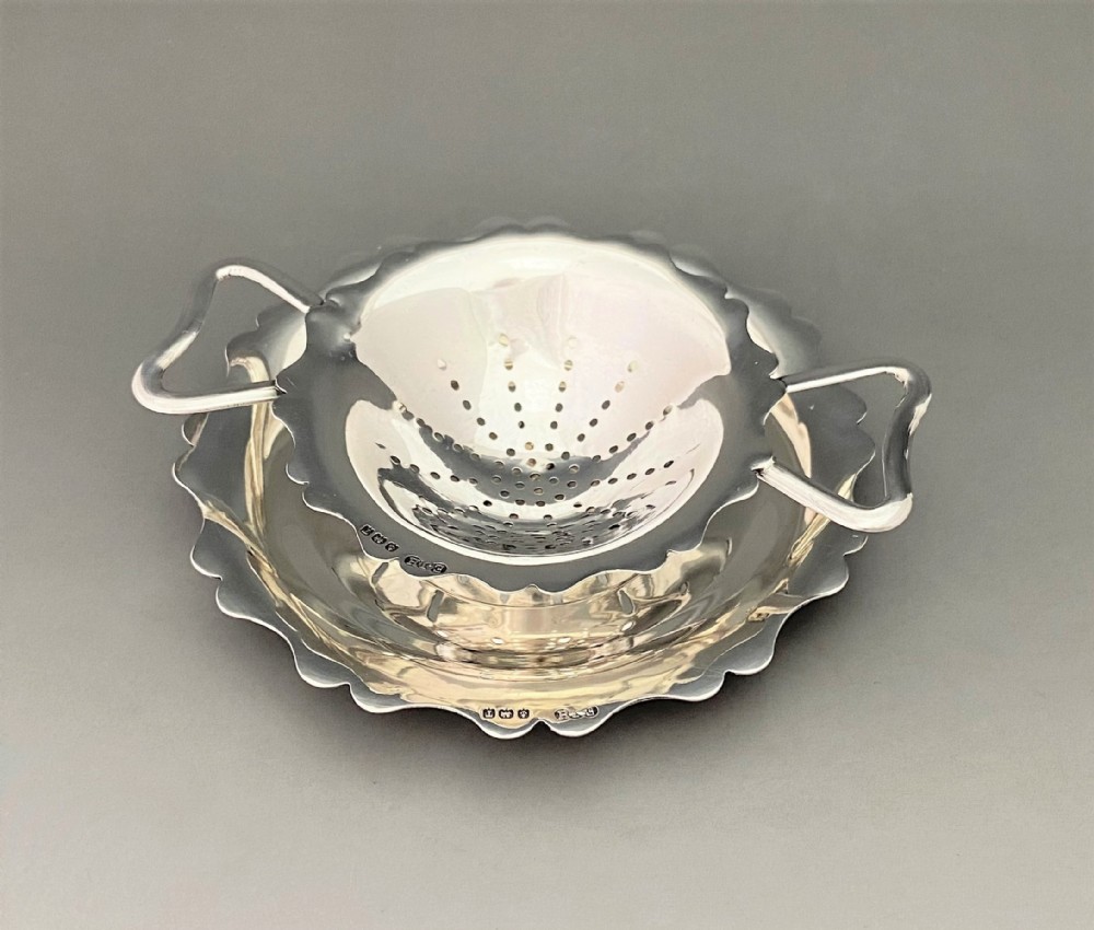 A stylish silver tea strainer & matching drip cup
