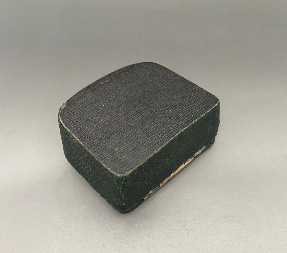 An antique dark green Georgian trinket box featuring a glass lid decorated with white, yellow, and green painted scrollwork motifs. View V