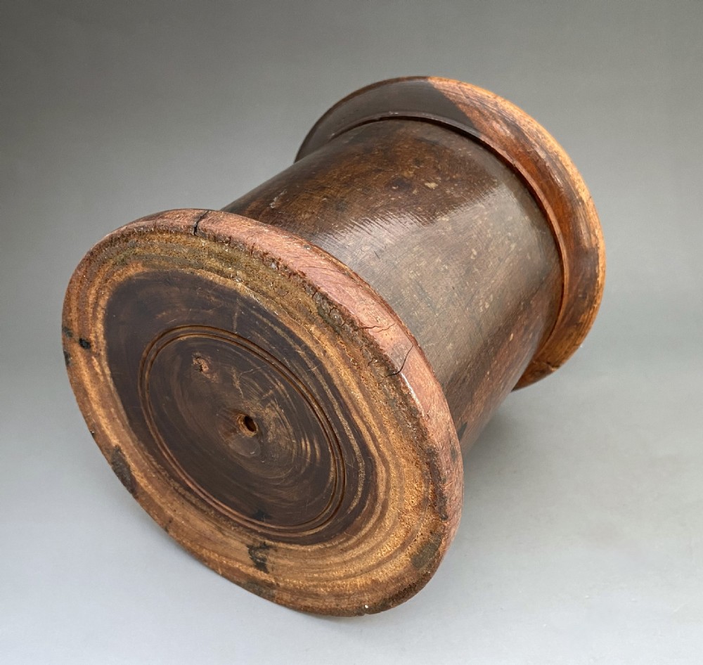 A cylindrical turned lignum vitae wooden string barrel with a raised central nozzle dispensing white string. View IV