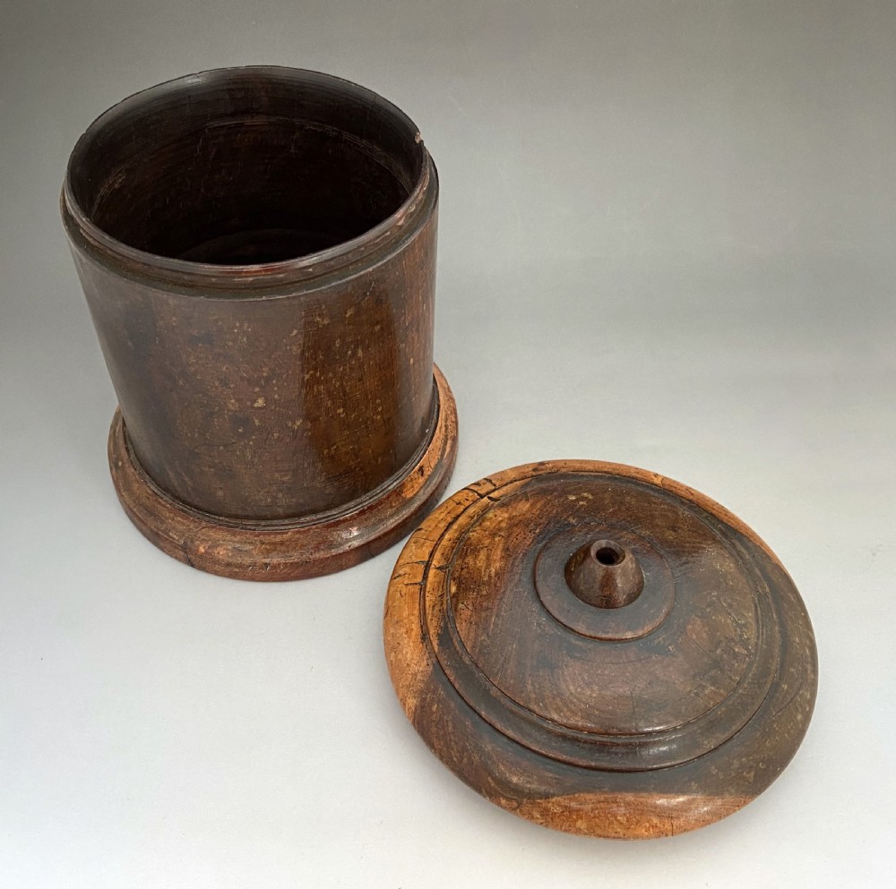 A cylindrical turned lignum vitae wooden string barrel with a raised central nozzle dispensing white string. View V