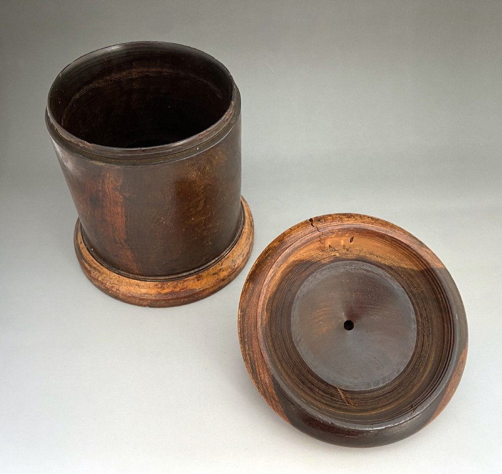 A cylindrical turned lignum vitae wooden string barrel with a raised central nozzle dispensing white string. View VI