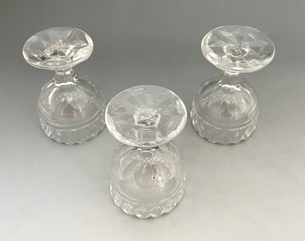 A trio of Georgian clear cut glass pedestal table salts featuring scalloped rims and diamond cutting. View III