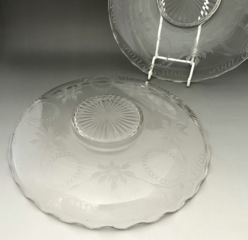 A pair of clear Edwardian glass plates featuring etched floral garlands, scalloped rims, and starburst cut centres. View IV