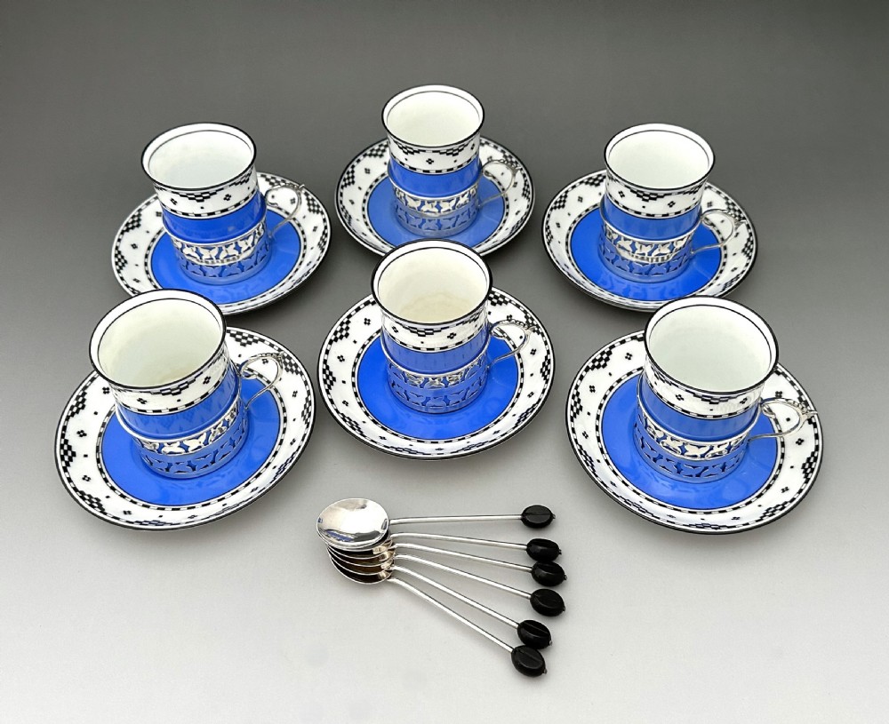 A set of six Art Deco blue porcelain coffee cans featuring pierced sterling silver mounts, matching saucers, and silver spoons with black coffee bean finials. View II