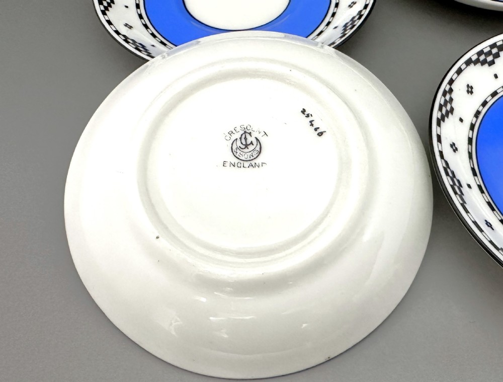 A set of six Art Deco blue porcelain coffee cans featuring pierced sterling silver mounts, matching saucers, and silver spoons with black coffee bean finials. View V