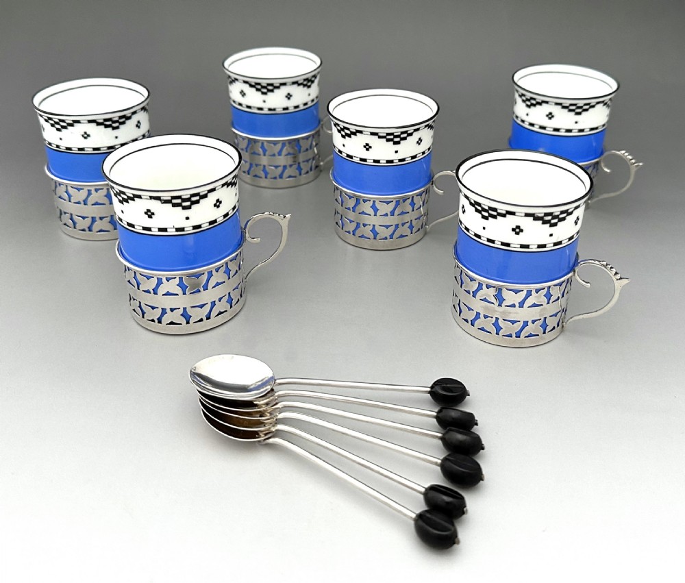A set of six Art Deco blue porcelain coffee cans featuring pierced sterling silver mounts, matching saucers, and silver spoons with black coffee bean finials. View VI